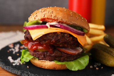 Tasty cheeseburger with patties, onion and pickles on table, closeup