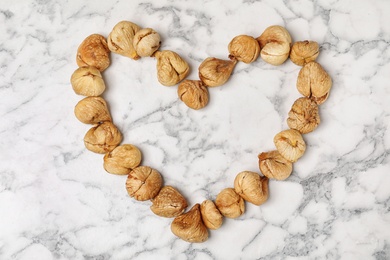 Photo of Heart made of figs on marble background, top view with space for text. Dried fruit as healthy food