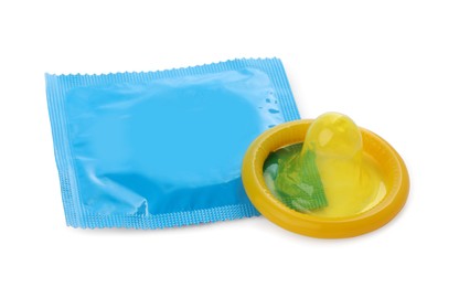 Photo of Package and unpacked yellow condom isolated on white. Safe sex