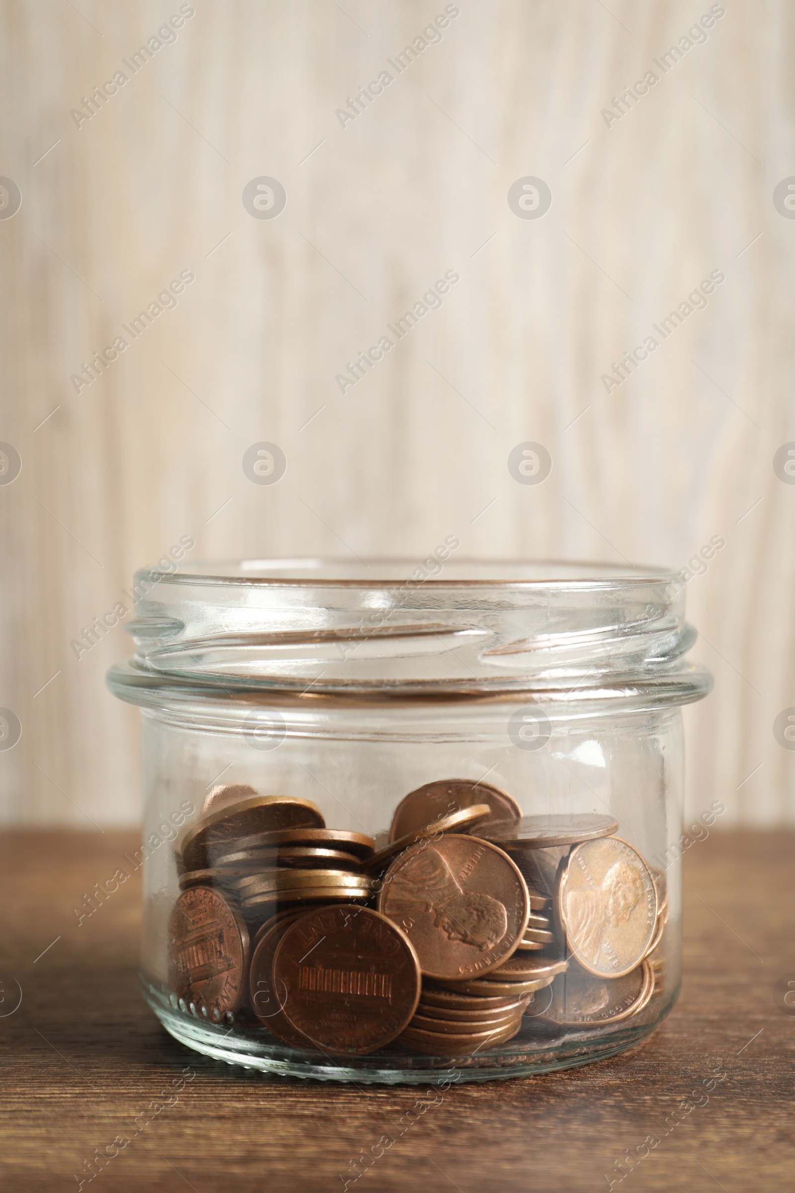 Photo of Glass jar with coins on wooden table, closeup