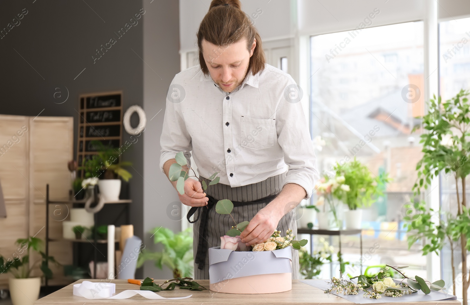 Photo of Male florist creating floral composition at workplace