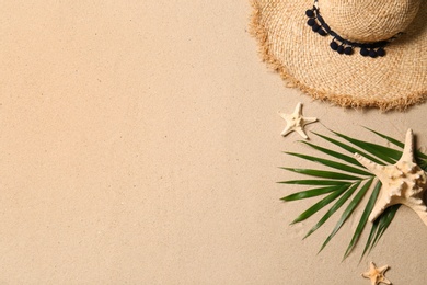 Photo of Straw hat, palm leaf, starfishes and space for text on beach sand, flat lay. Summer vacation