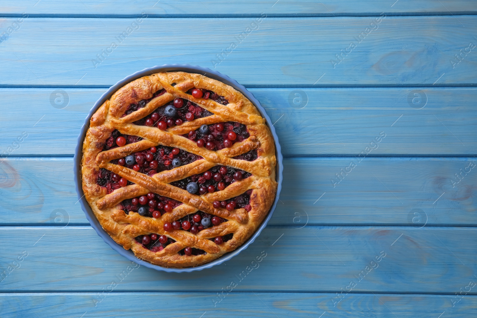 Photo of Delicious currant pie and fresh berries on blue wooden table, top view. Space for text