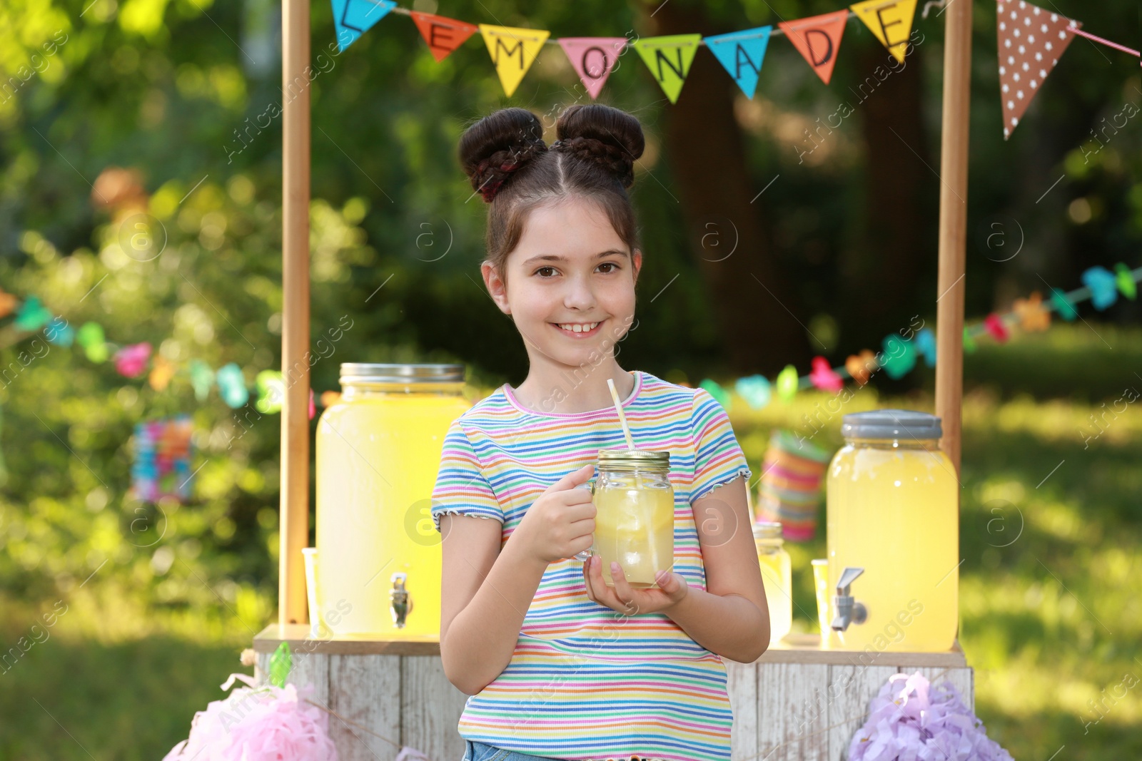 Photo of Cute little girl with natural lemonade in park. Summer refreshing drink