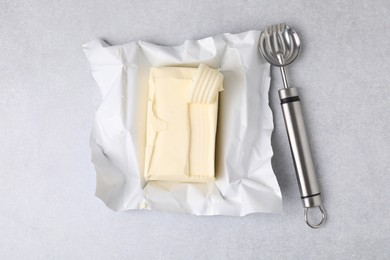 Photo of Tasty butter with curl and spoon on light grey table, top view