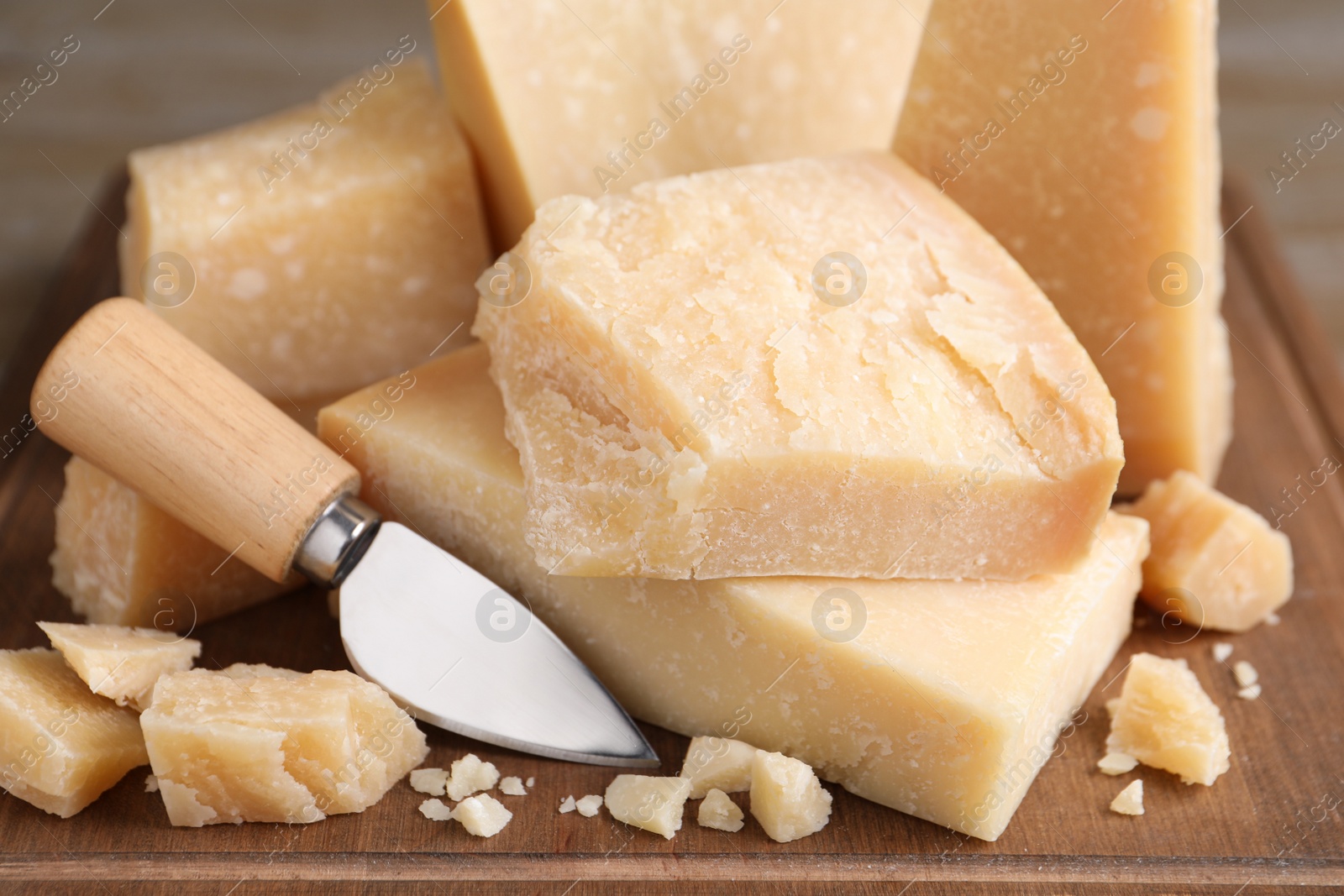 Photo of Delicious parmesan cheese with knife on wooden board, closeup