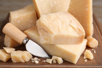 Photo of Delicious parmesan cheese with knife on wooden board, closeup