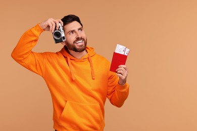 Smiling man with passport, camera and tickets on beige background. Space for text