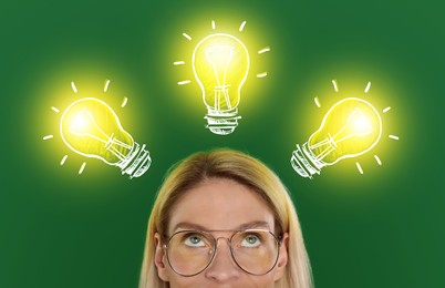 Image of Idea generation. Woman looking at illustrations of glowing light bulb over her on green background