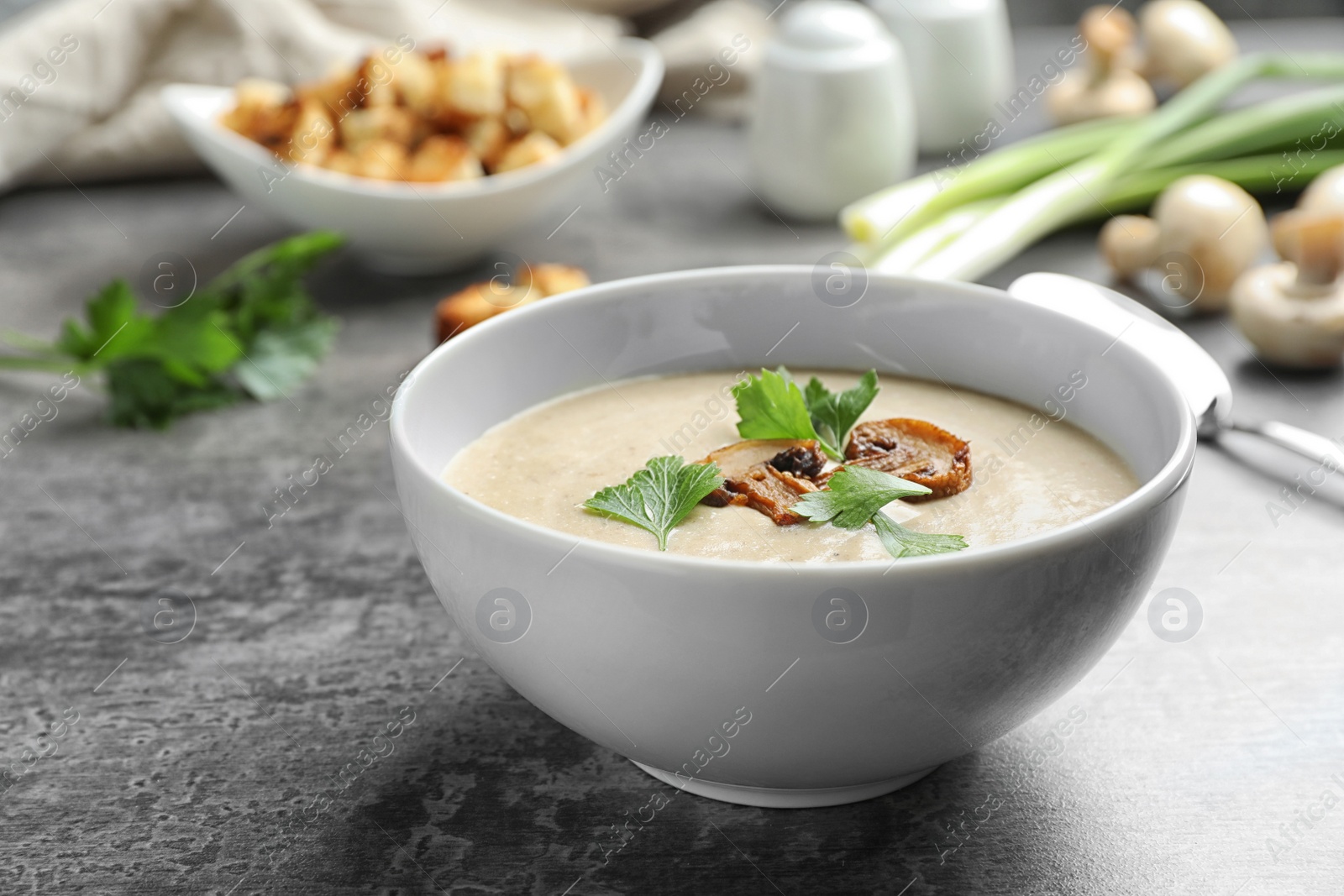 Photo of Bowl of fresh homemade mushroom soup on gray table