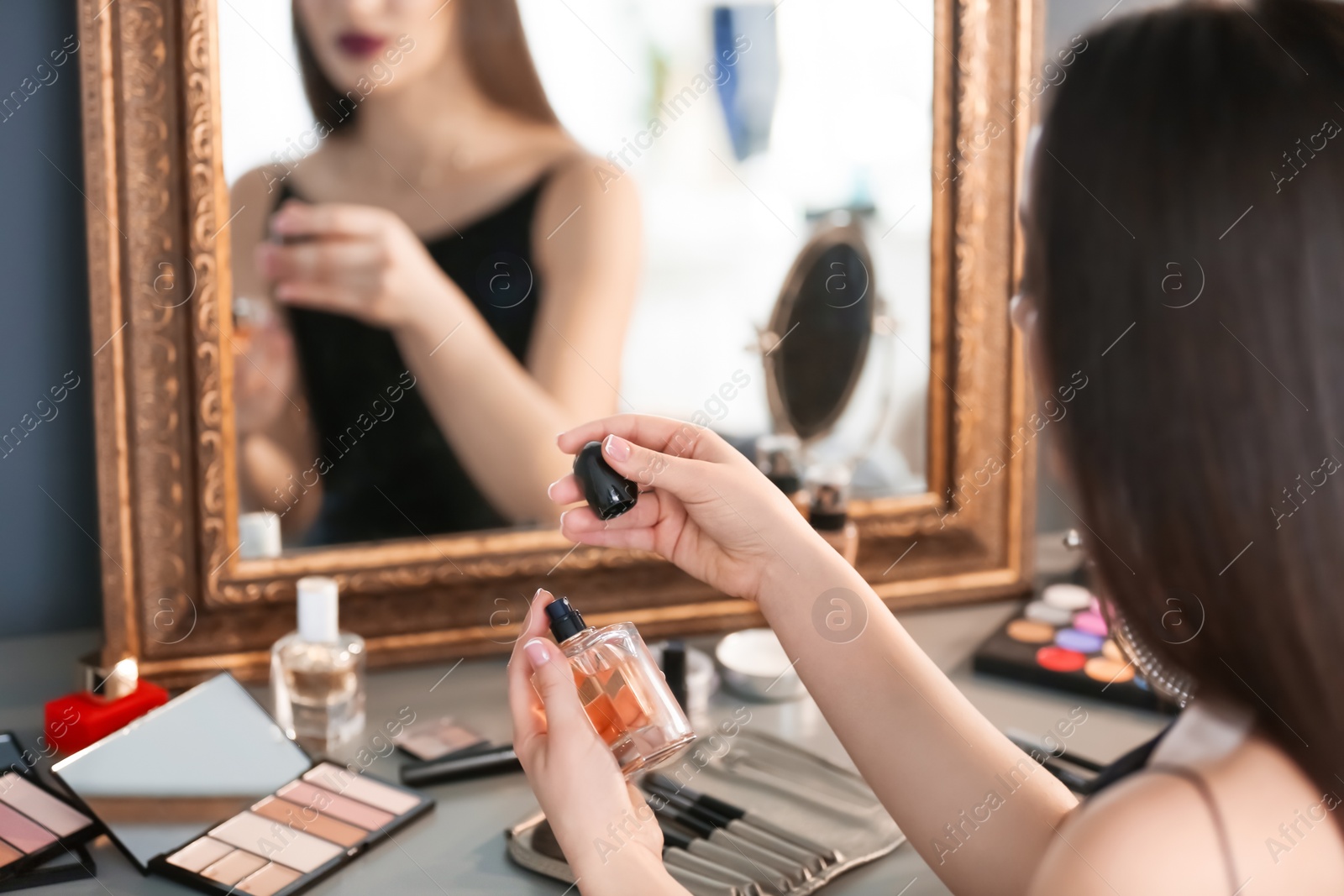 Photo of Young woman applying perfume in makeup room, closeup