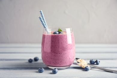 Tasty blueberry smoothie in glass, berries and oatmeal on wooden table