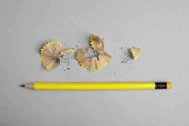 Pencil and shavings on grey background, top view