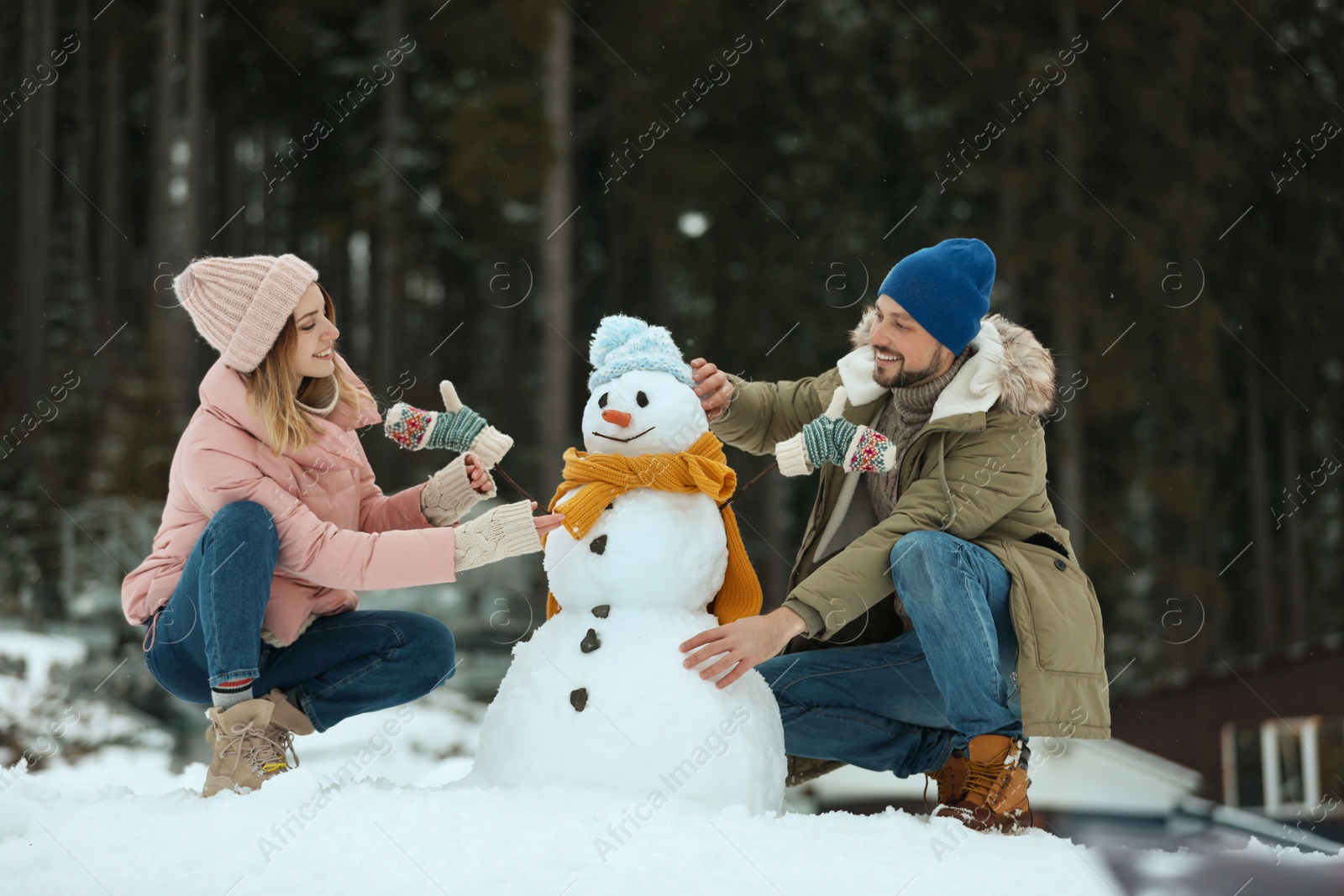 Photo of Couple making snowman outdoors. Winter vacation