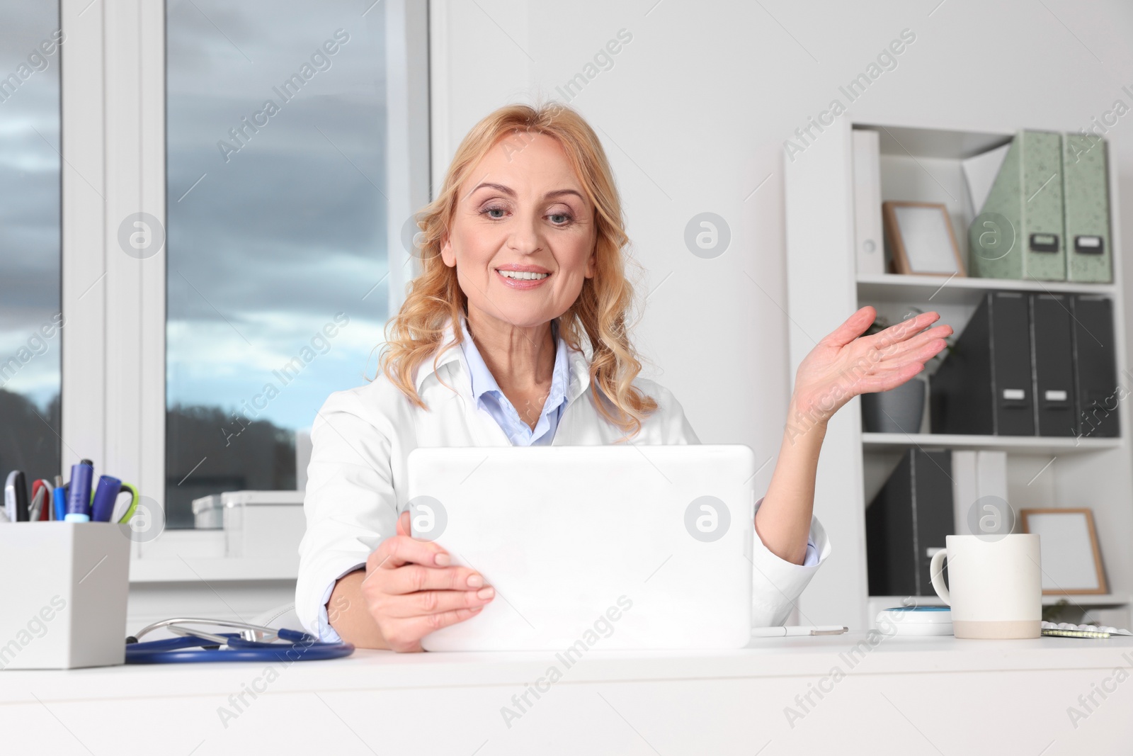 Photo of Doctor with tablet consulting patient in clinic. Online medicine concept