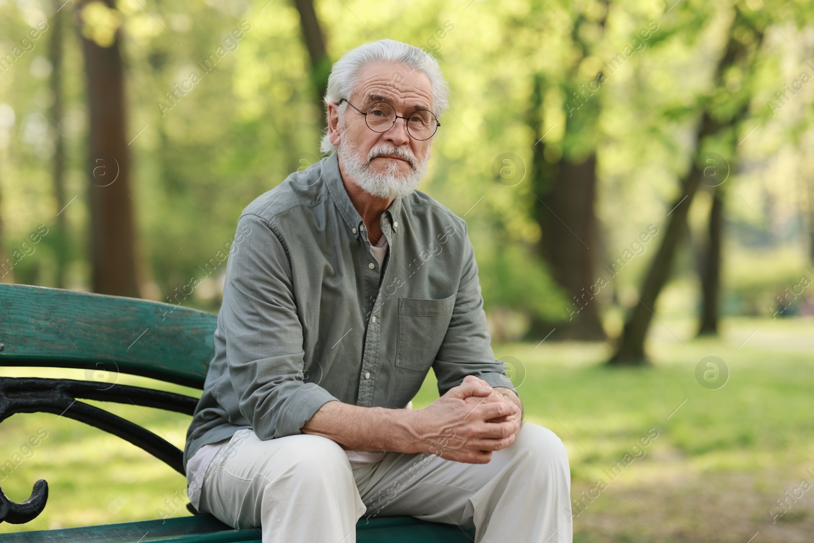 Photo of Portrait of happy grandpa with glasses on bench in park