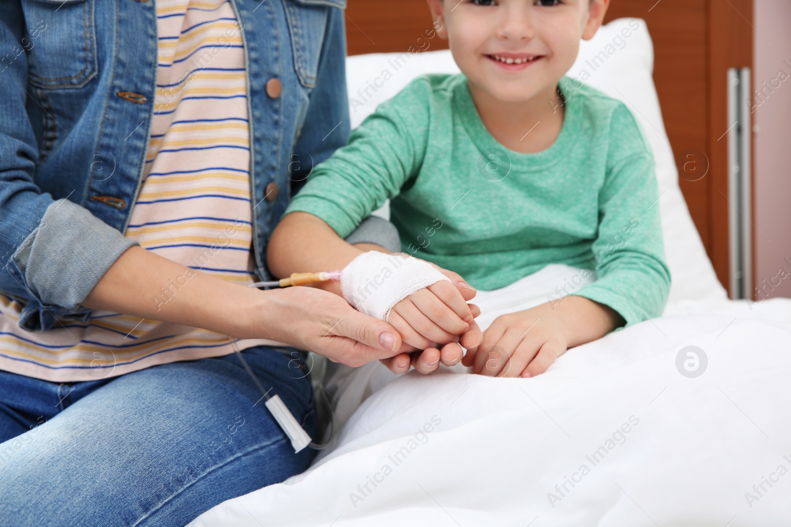 Photo of Woman visiting her little child with intravenous drip in hospital, closeup