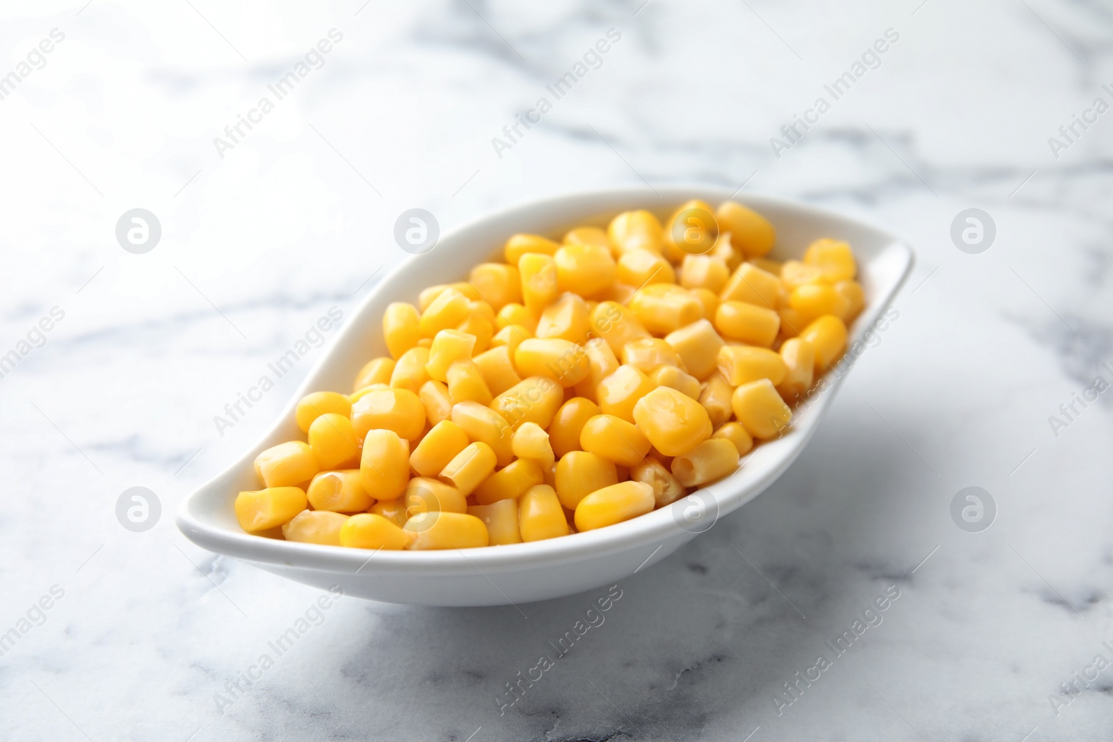 Photo of Bowl with corn kernels on marble background