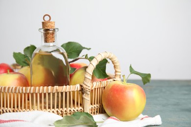 Photo of Natural apple vinegar and fresh fruits on blue wooden table. Space for text