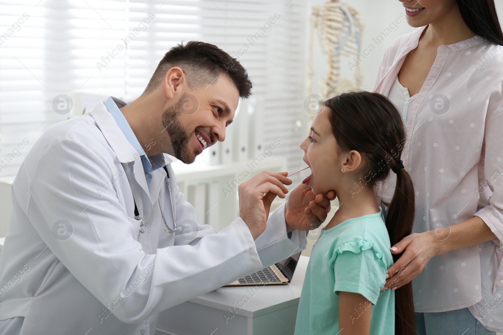 Photo of Mother with daughter visiting pediatrician in hospital. Doctor examining little girl