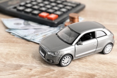 Photo of Toy car and money on table. Vehicle insurance