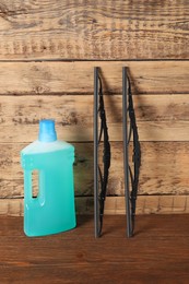 Photo of Bottle of windshield washer fluid and wipers on wooden table