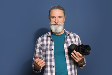 Photo of Male photographer with professional camera on color background