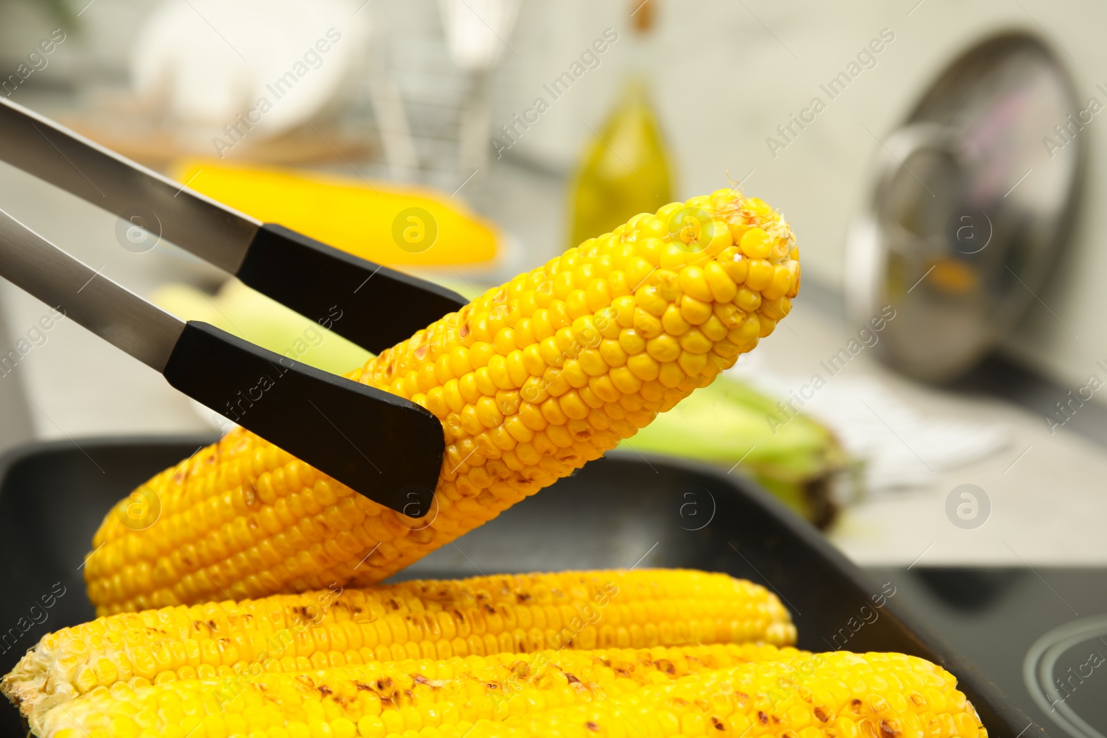 Photo of Cooking fresh corn cobs on grill pan, closeup