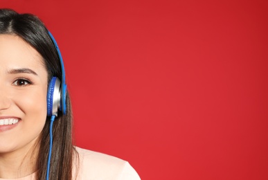 Photo of Attractive young woman enjoying music in headphones on color background. Space for text