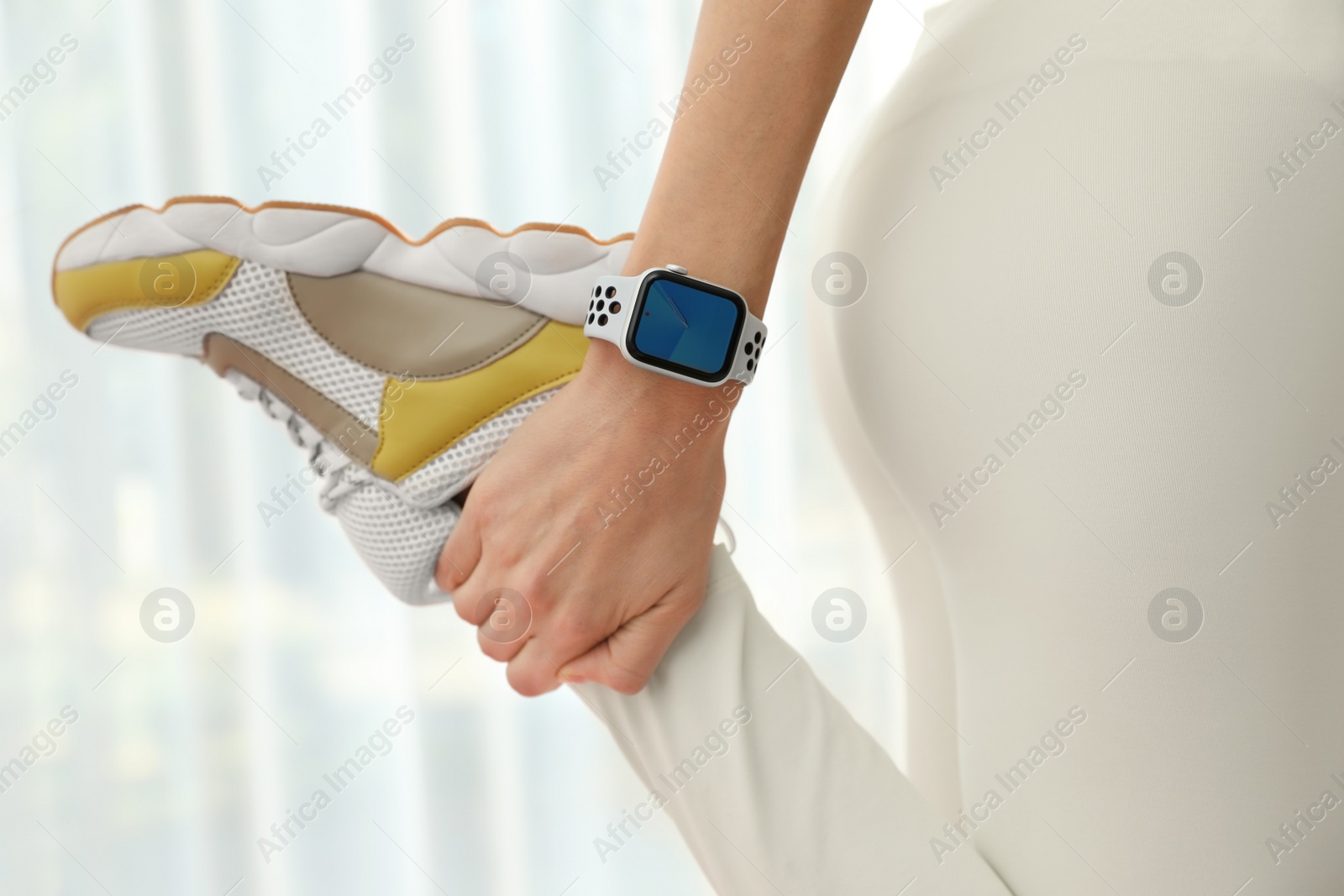 Photo of Young woman wearing smart watch during training indoors, closeup