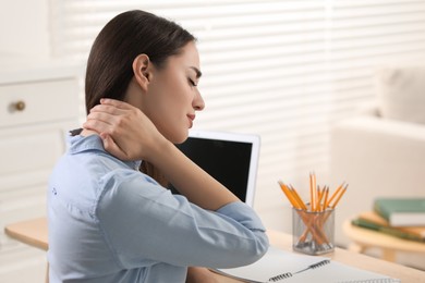 Photo of Young woman suffering from neck pain at table in office