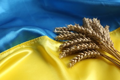 Photo of Ears of wheat on Ukrainian national flag, space for text