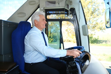 Photo of Professional bus driver at steering wheel. Passenger transportation