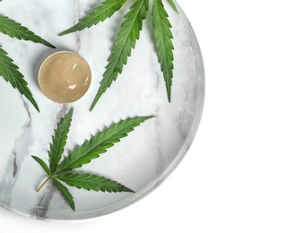 Photo of Plate with bowl of hemp lotion and leaves on light background, top view