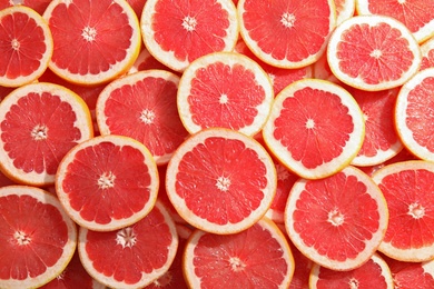 Photo of Many sliced fresh grapefruits as background, top view