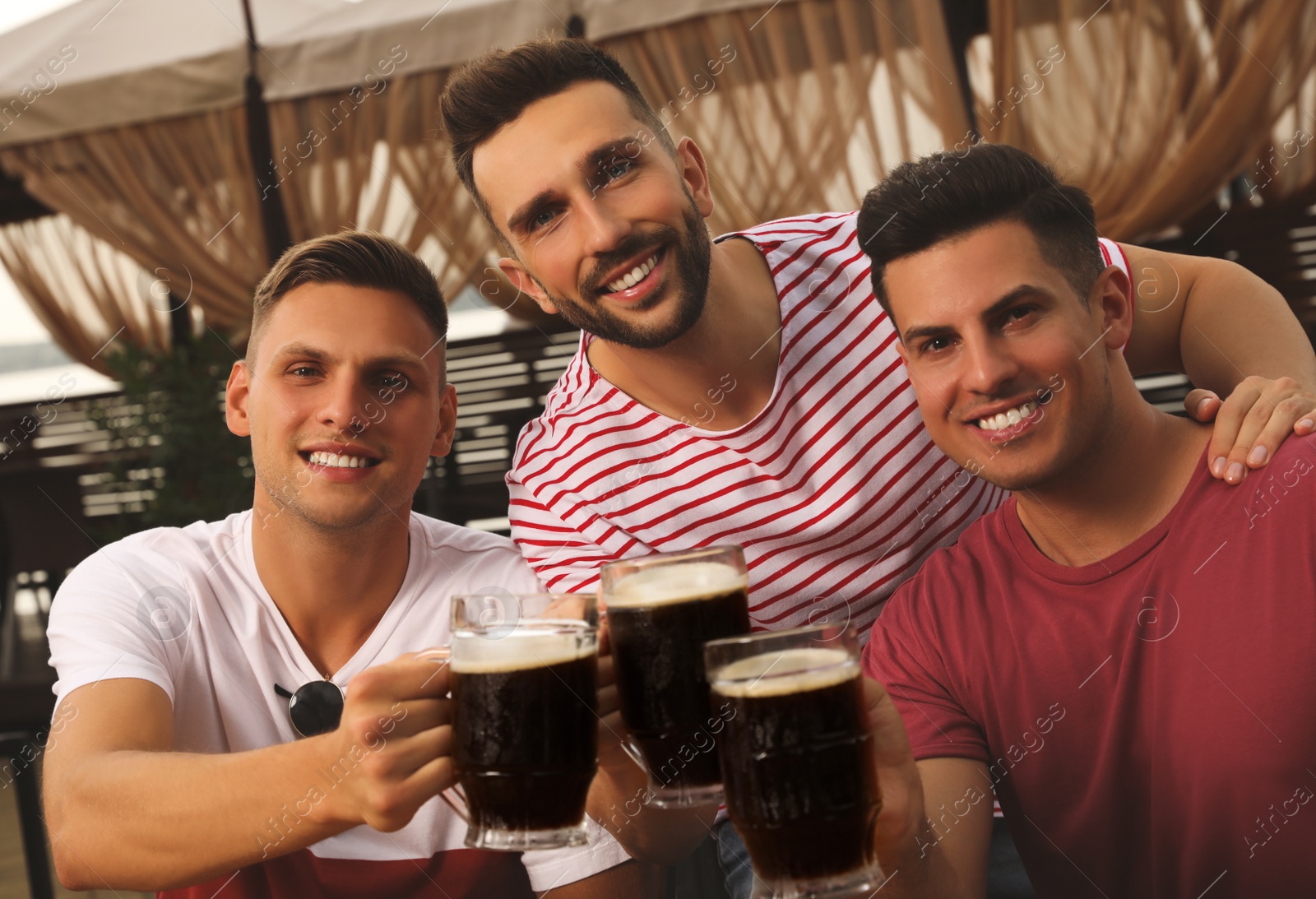 Photo of Friends clinking glasses of beer in outdoor cafe