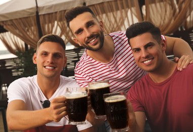 Friends clinking glasses of beer in outdoor cafe