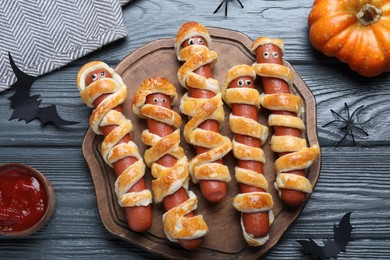 Cute sausage mummies served on wooden table, flat lay. Halloween party food