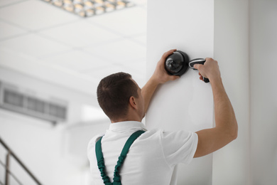 Technician installing CCTV camera on wall indoors