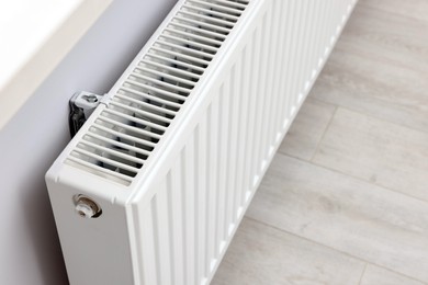 Photo of Modern radiator on white wall in room, closeup. Central heating system