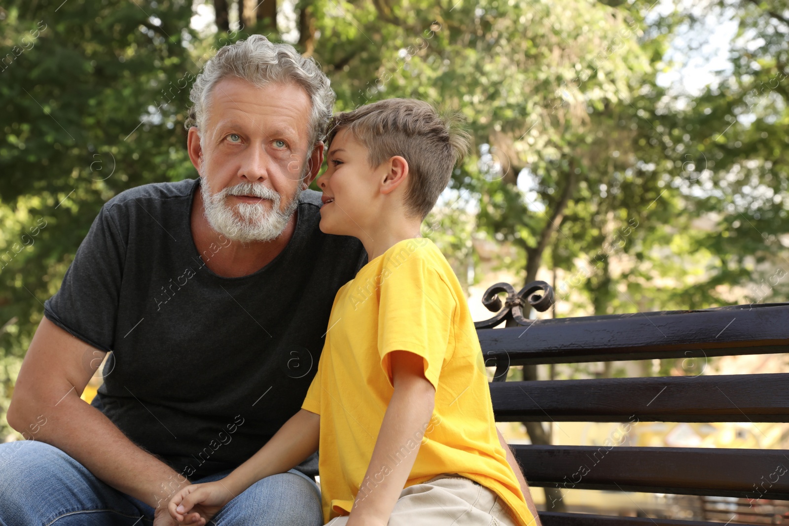 Photo of Senior man with his little grandson resting together in park