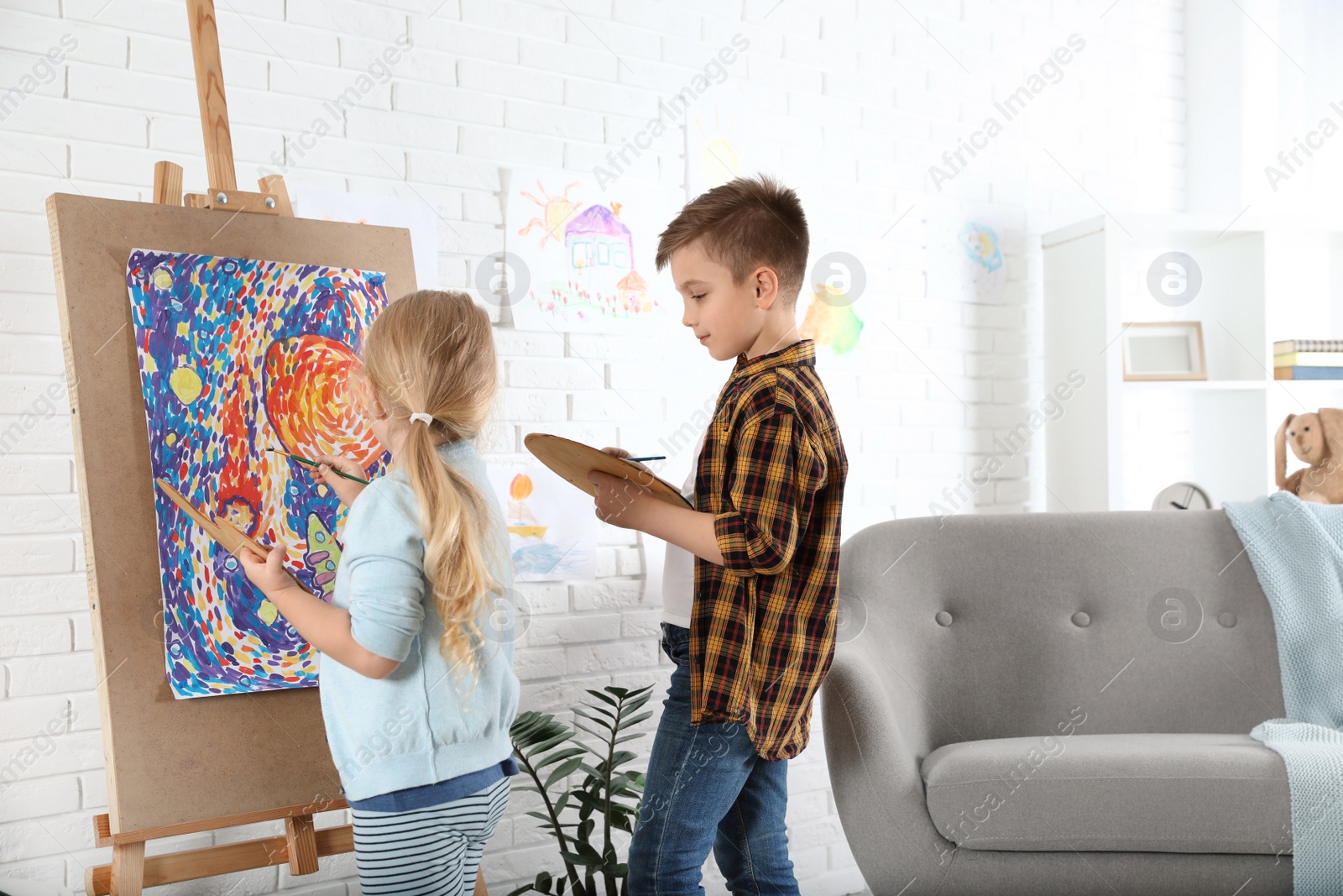 Photo of Cute little children painting on easel at home