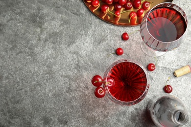 Photo of Delicious cherry wine with ripe juicy berries on grey table, flat lay. Space for text