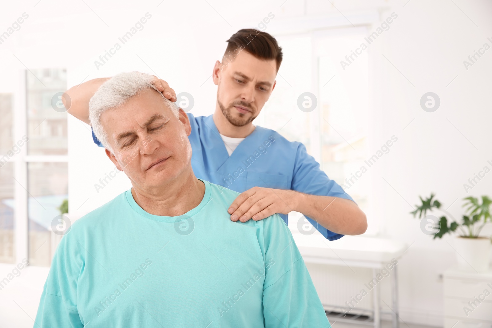 Photo of Young physiotherapist working with senior patient in clinic