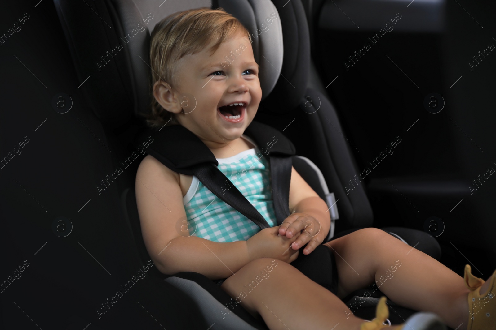 Photo of Cute little girl sitting in child safety seat inside car