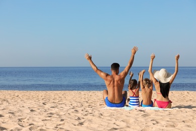 Photo of Family on sandy beach near sea, back view. Summer holidays