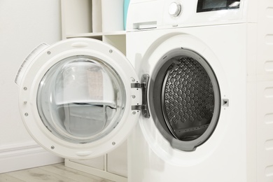 Photo of Modern washing machine in light laundry room