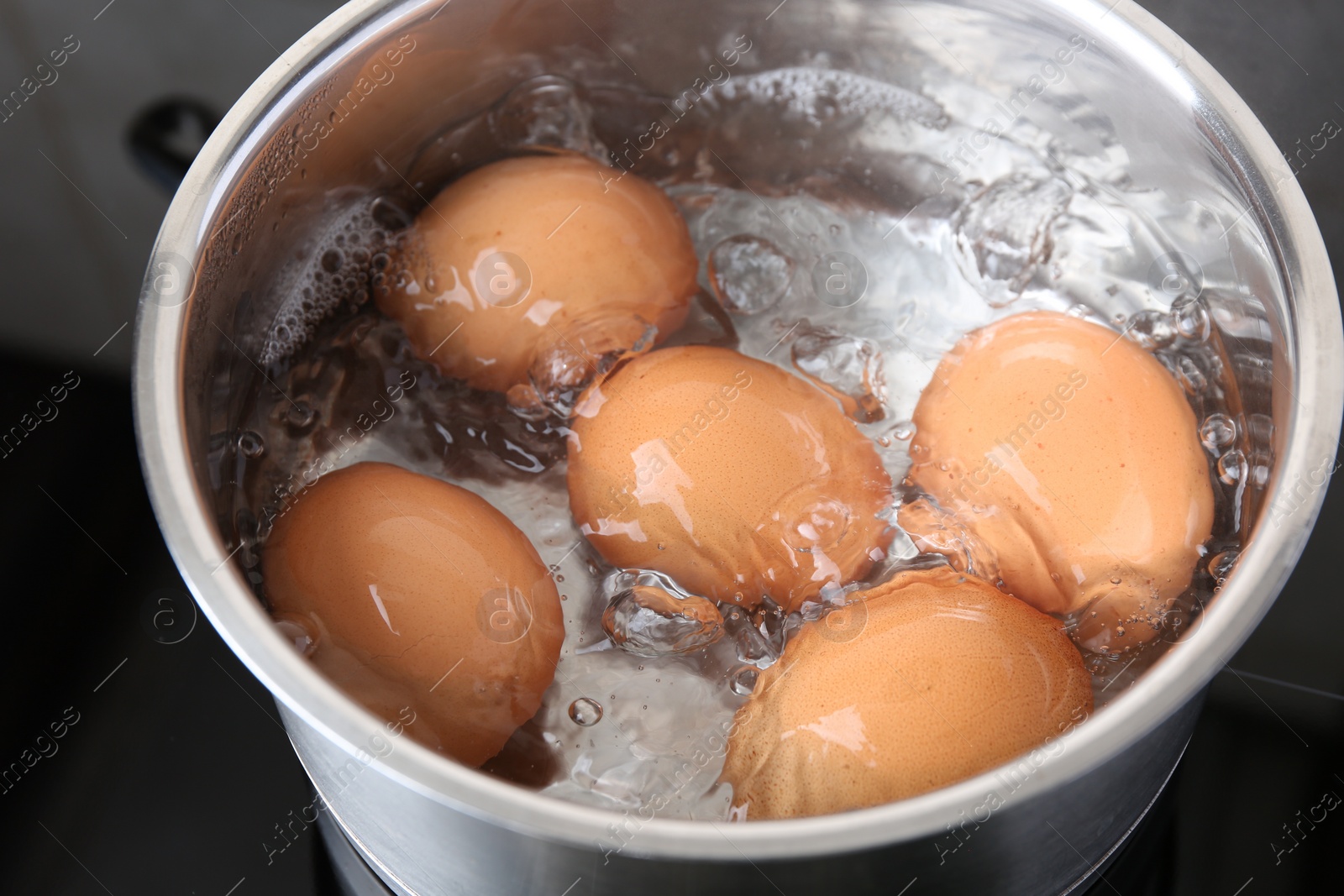 Photo of Chicken eggs boiling in saucepan on electric stove, closeup