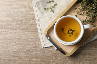 Photo of Cup of fresh thyme tea on wooden table, flat lay. Space for text