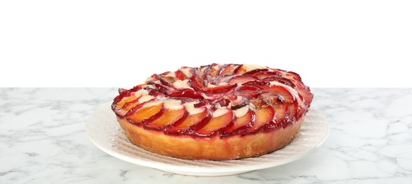 Photo of Delicious plum cake on marble table against white background